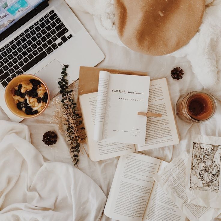 an open book sitting on top of a bed next to a cup of coffee and a laptop