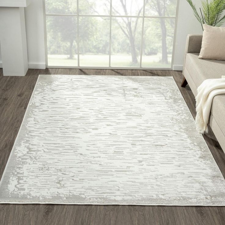 a living room area with a couch, chair and rug on the hardwood flooring