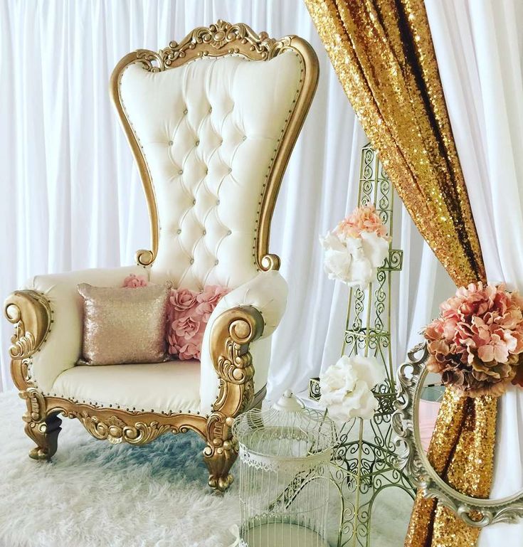 a fancy chair and mirror in front of a white curtain with gold sequins