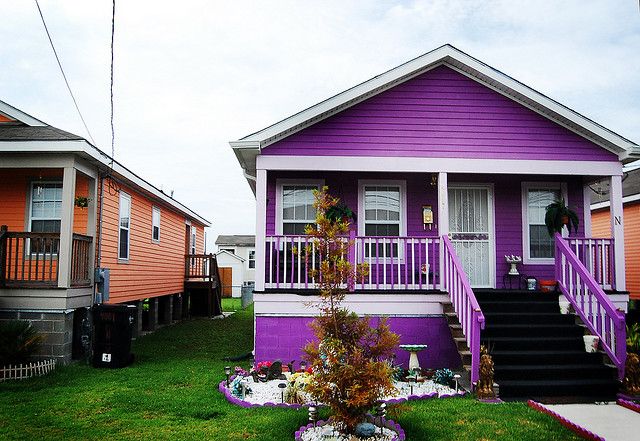 purple and orange houses with stairs leading up to the front door, on green grass