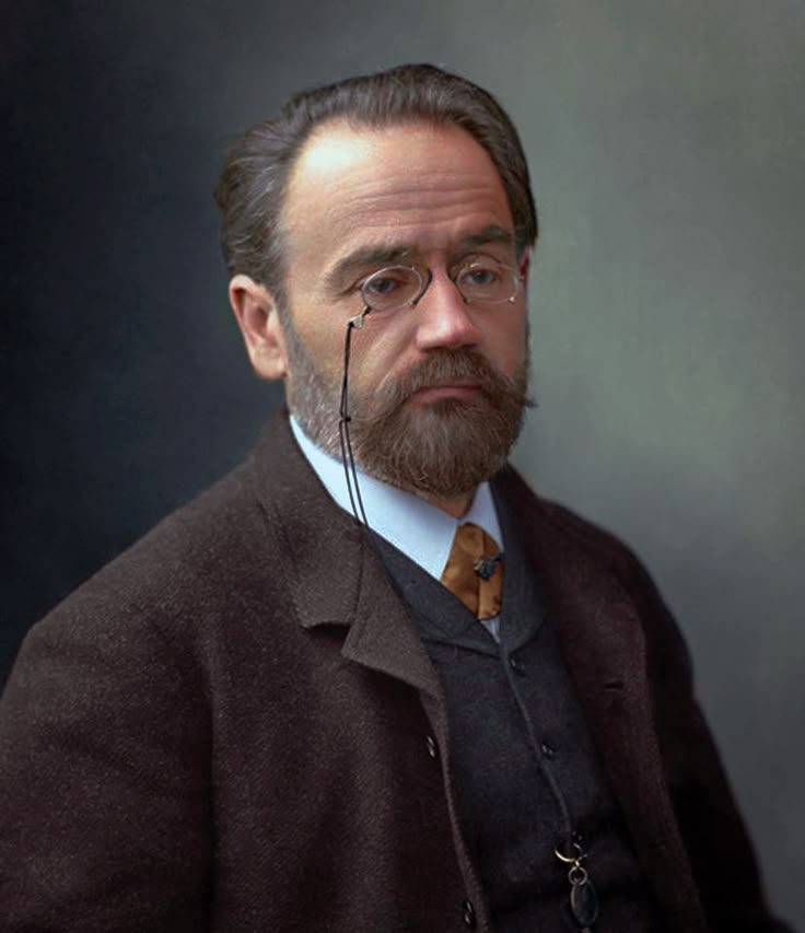 a man with glasses and a beard wearing a coat, tie and eyeglasses