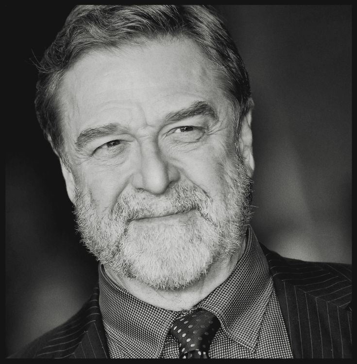 a black and white photo of a man with a beard wearing a suit and tie