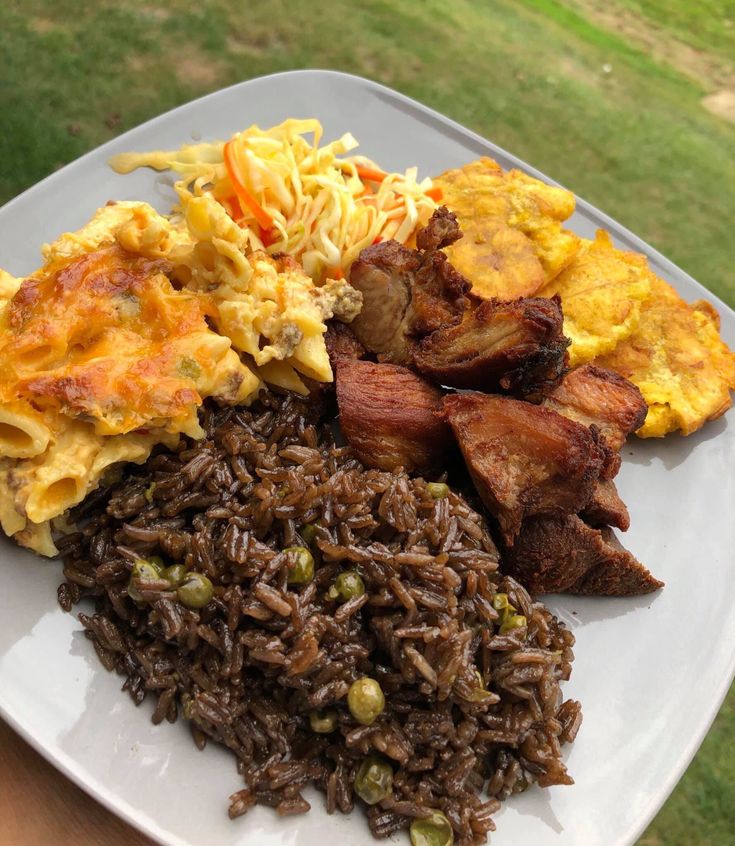 a white plate topped with lots of food on top of a wooden table next to a green field