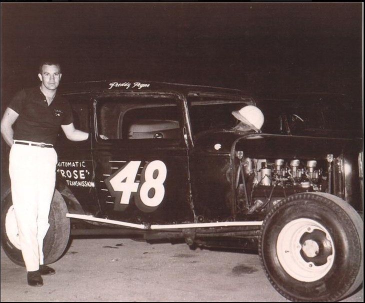 an old black and white photo of a man standing next to a car with the number 48 on it