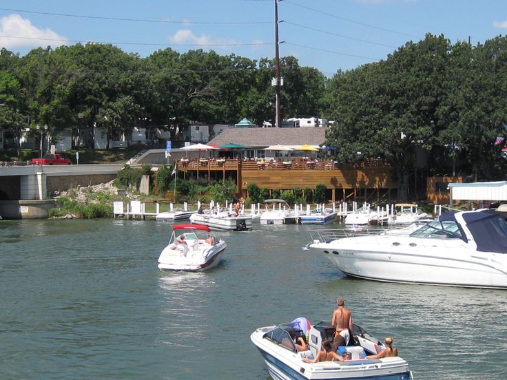 several boats are in the water and some people are riding on one boat while another is driving off into the distance