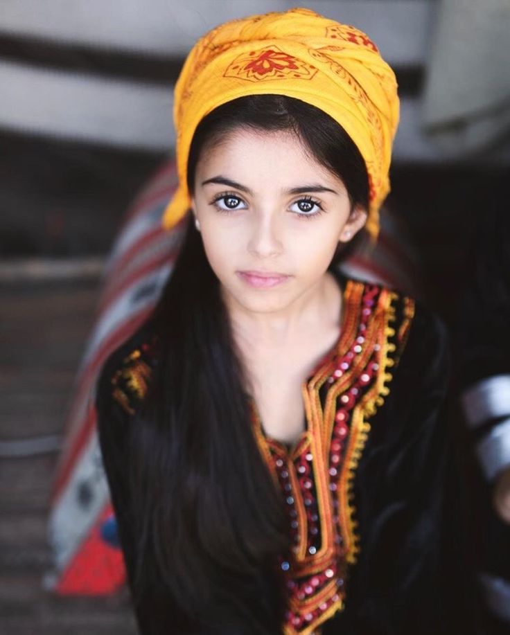 a woman wearing a yellow turban sitting on top of a wooden floor next to a wall