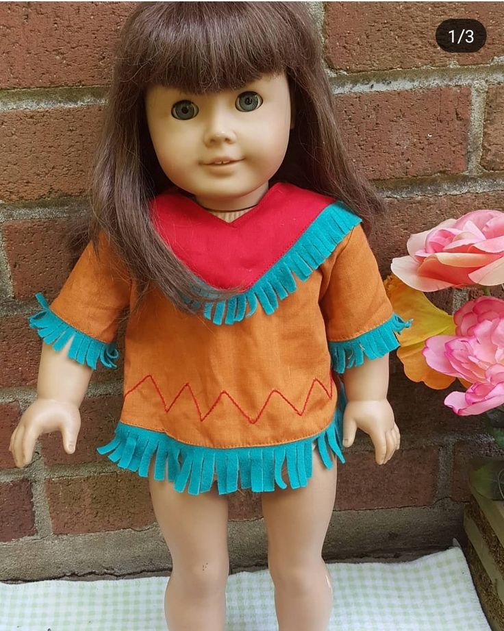 a doll is standing next to a brick wall with flowers in it's hand