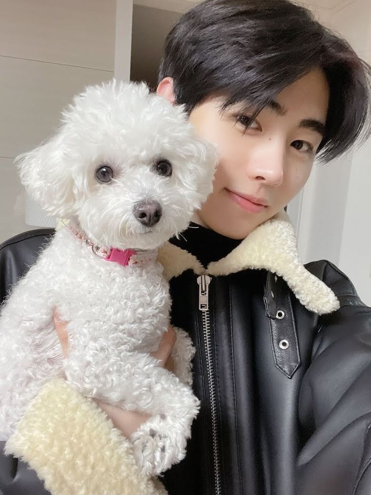 a woman is holding a white dog in her arms while wearing a black leather jacket