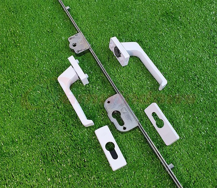 two pieces of white plastic sitting on top of green grass next to metal handles and latches