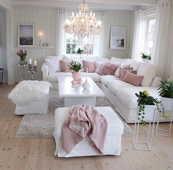 a living room filled with furniture and a chandelier hanging above the couches