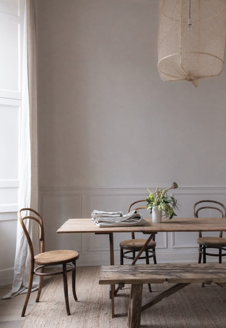 a wooden table and two chairs in a room with a light fixture hanging over it