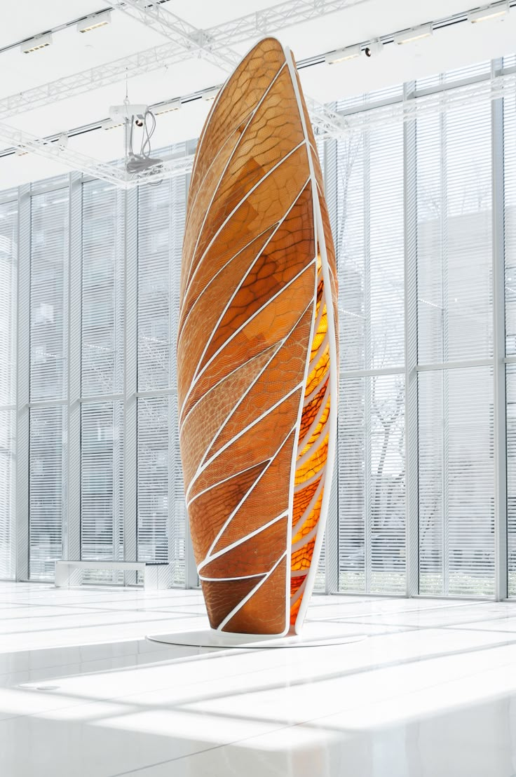 a large wooden sculpture sitting in the middle of a room with lots of glass walls