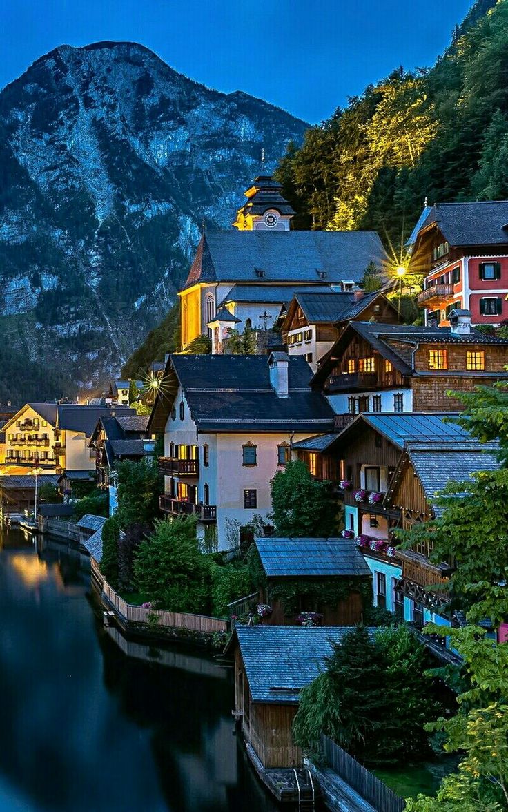 a scenic view of a town with mountains in the background and water running through it