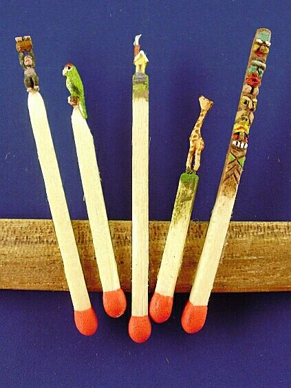 four matches are lined up in a row on top of a blue surface, with small birds perched on them