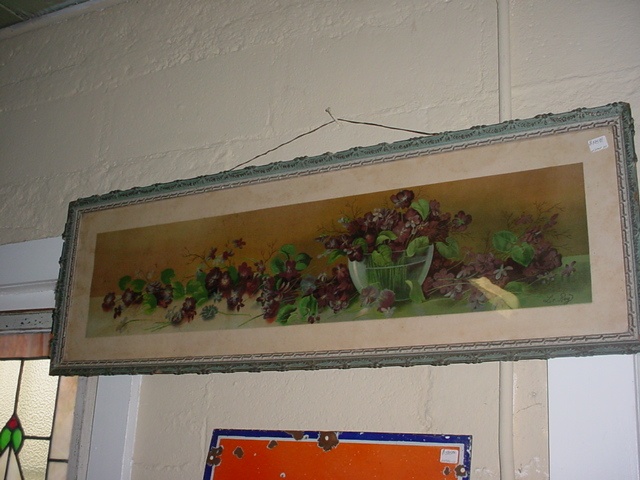 a painting hanging on the wall above a window with a sign below it that reads, lettuce and red berries