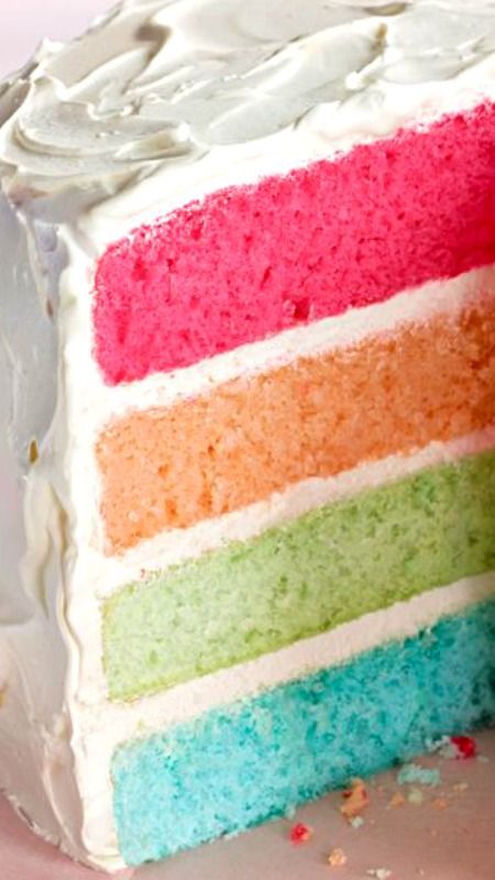 a slice of rainbow cake with white frosting