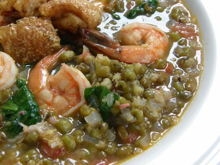 a white bowl filled with shrimp, peas and other food items on top of it