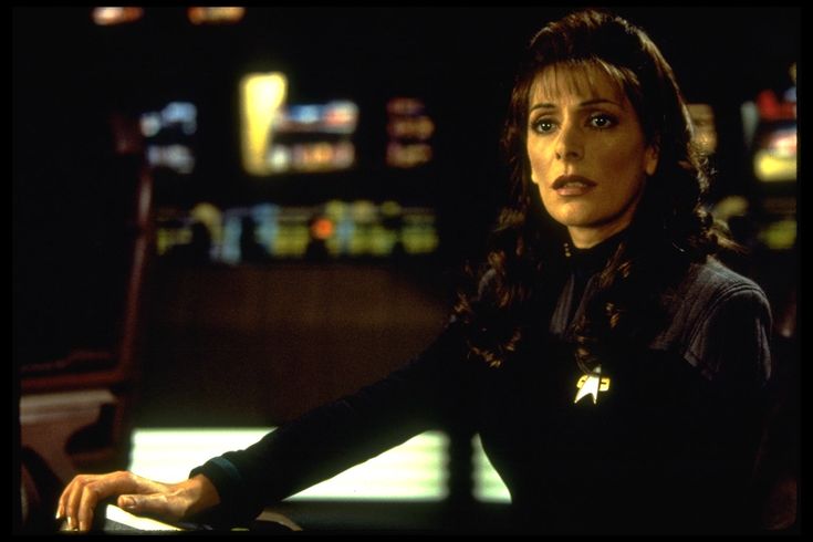 a woman sitting at a table in front of a computer screen with the words star trek written on it