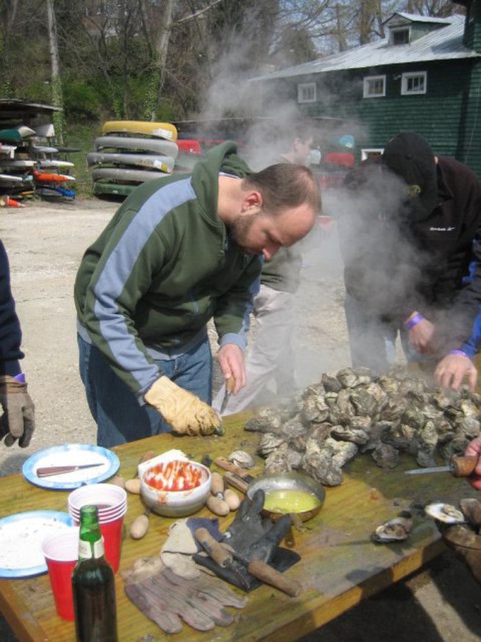 three men preparing food on top of a wooden table