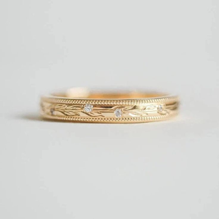 a gold wedding band with three diamonds on the inside and outside, set in 18k yellow gold