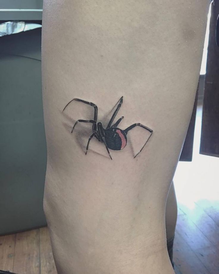 a black and red spider tattoo on the right side of the leg, it appears to be an insect