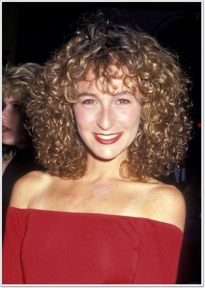 a close up of a person wearing a red dress and smiling at the camera with curly hair