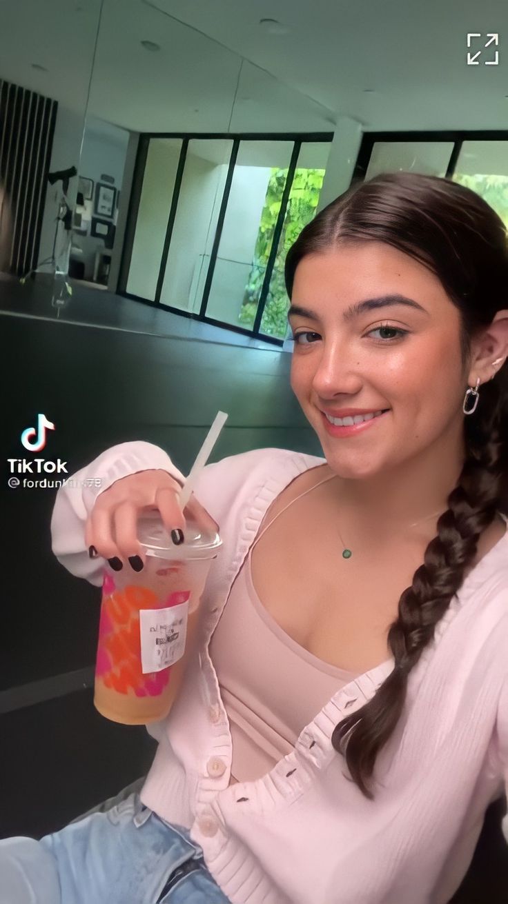 a woman sitting down holding a drink in one hand and a straw in the other