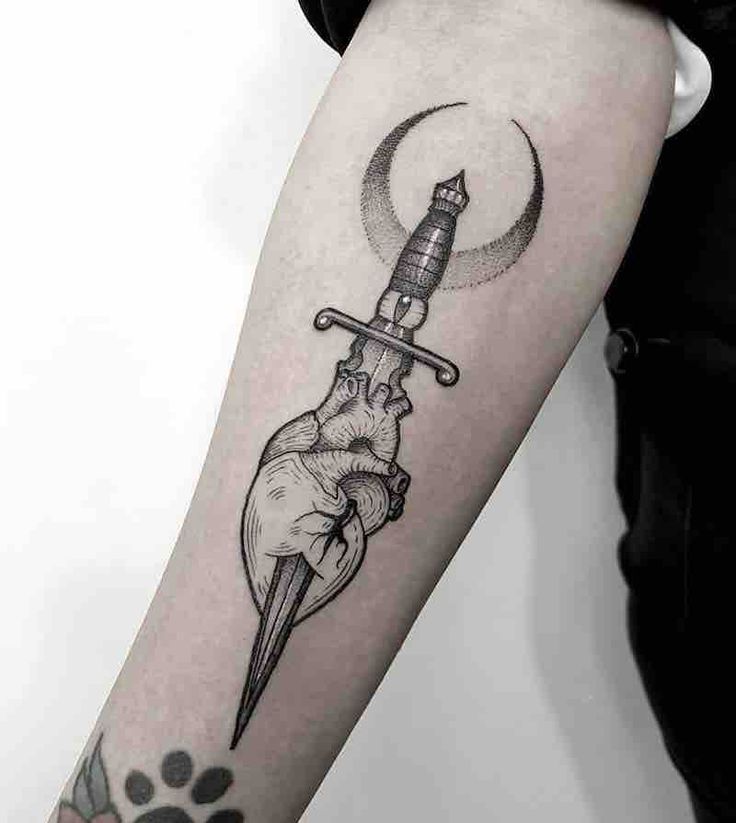 a person with a tattoo on their arm holding a dagger and a dog's paw