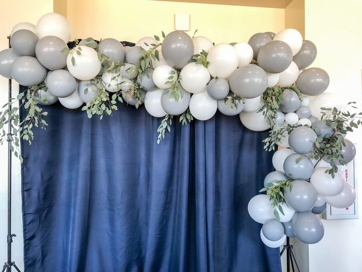 balloons and greenery decorate the backdrop for an event