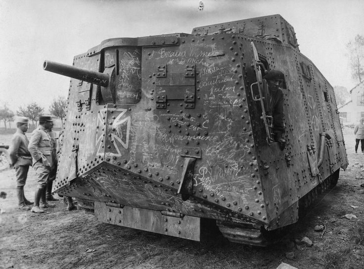 an old tank sitting on top of a dirt field next to other men and women