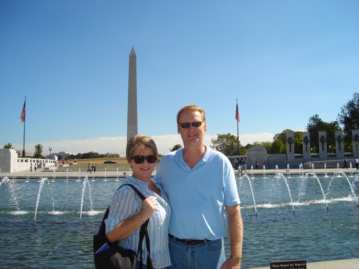 a man and woman standing in front of a fountain with the washington monument in the background