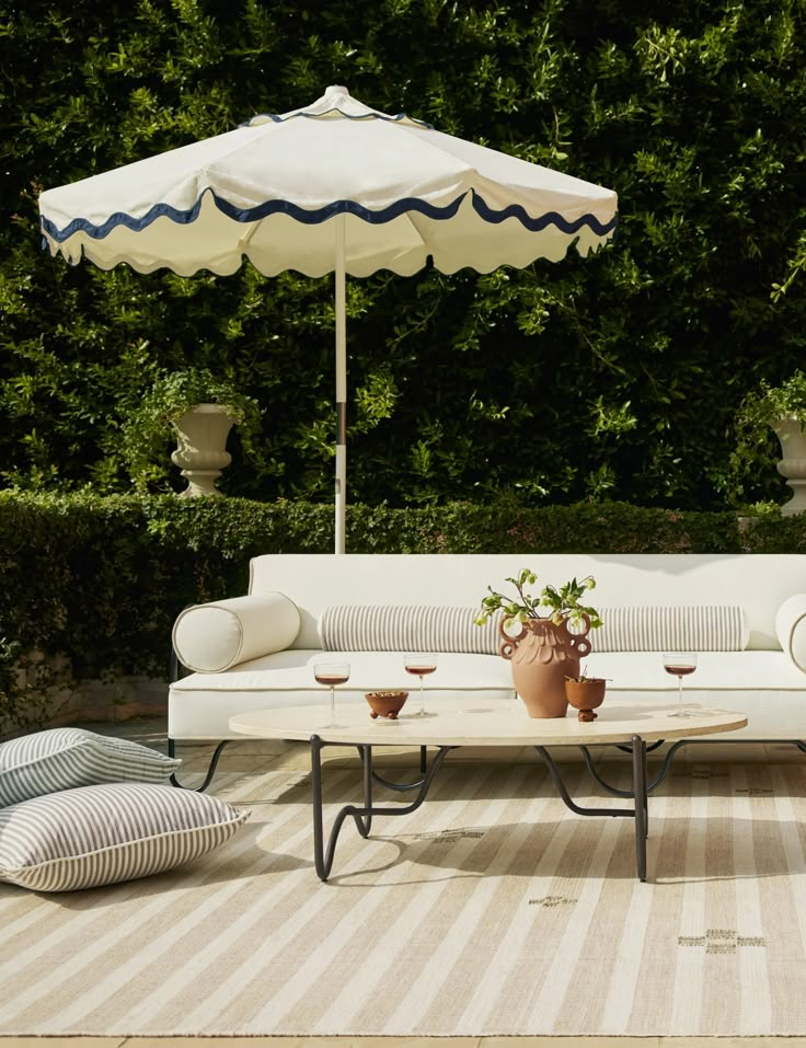 a white couch sitting on top of a wooden floor next to a table and umbrella