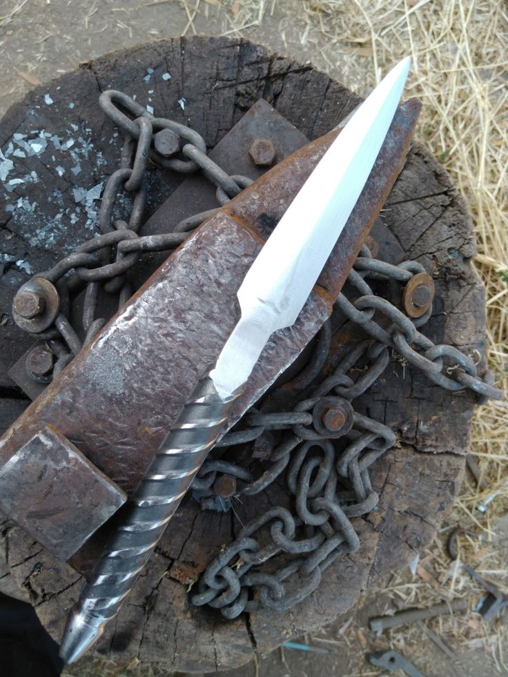 an old knife and chain on top of a piece of wood with chains around it