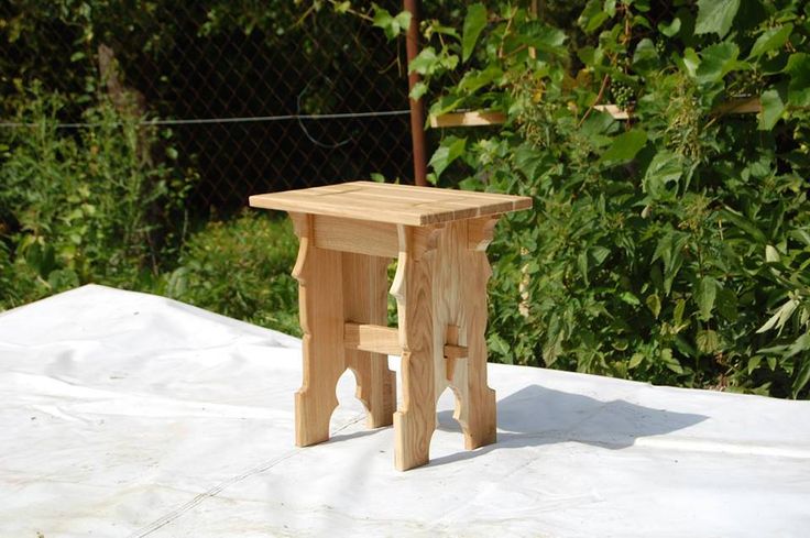 a small wooden stool sitting on top of a white sheet