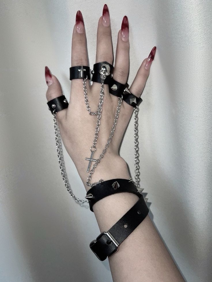 This uniquely designed bracelet features an integrated ring, connected by a stylish chain that adds a touch of avant-garde elegance. The bracelet is adorned with stud embellishments, while the ring showcases intricate decorations including skeleton motifs, crosses, and additional studs.  Please note that the price includes one bracelet with rings.  Ring Diameters: - Thumb, Index, and Middle Fingers: 6.5 cm - Ring and Pinky Fingers: 6 cm Party Jewelry With Metal Decoration, Punk Style Metal Body Jewelry With Chain, Edgy Adjustable Metal Chain Bracelet, Adjustable Metal Punk Chain Bracelet, Adjustable Metal Chain Bracelet, Punk Style, Adjustable Edgy Metal Chain Bracelet, Punk Black Jewelry With Chain Strap, Black Punk Jewelry With Chain Strap, Emo Style Party Jewelry With Chain