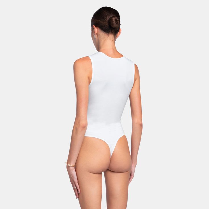 a woman in a white bodysuit with her back to the camera