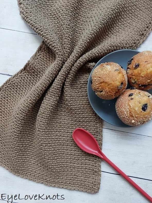 three blueberry muffins on a plate with a red spoon next to it