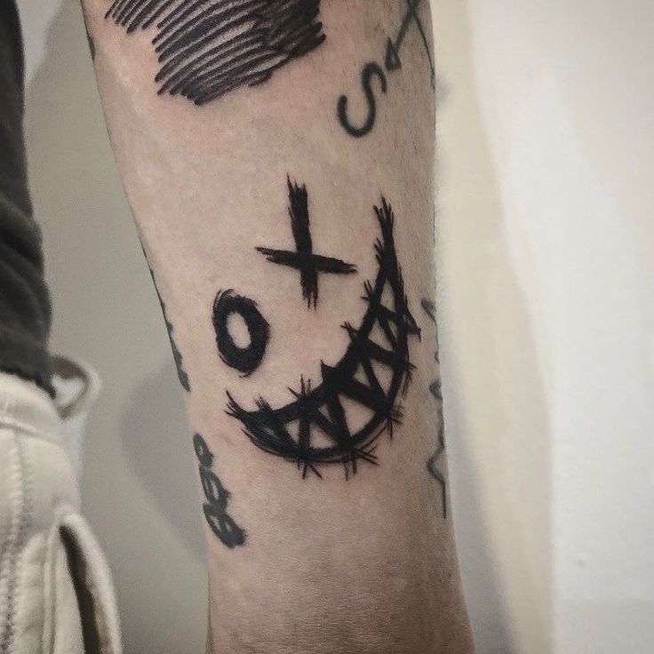 a person with a tattoo on their arm that has a cross and smile drawn on it