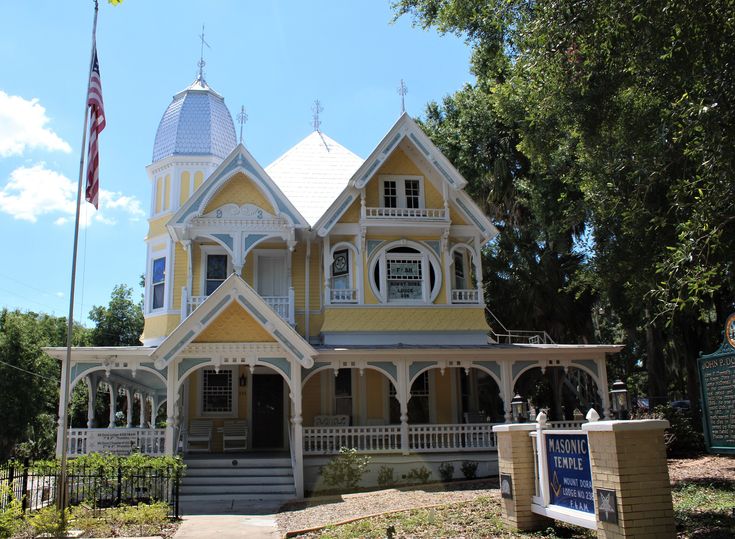 a yellow and white house with a flag flying in the wind