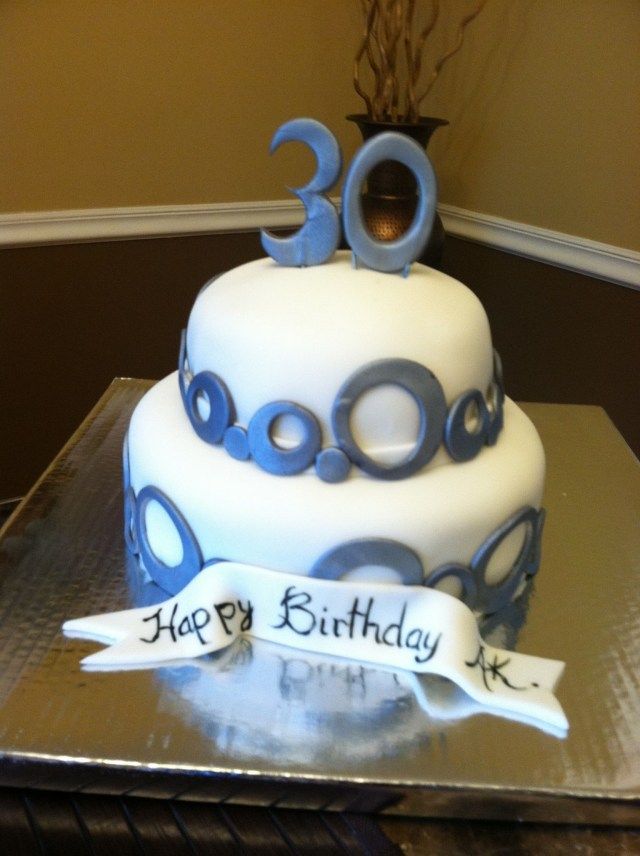 a white and blue birthday cake sitting on top of a table