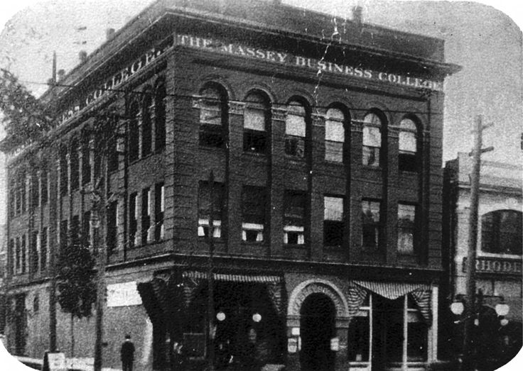 an old black and white photo of a tall building on the corner of a street