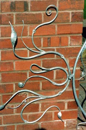 a metal sculpture on the side of a brick wall with an artistic design in it