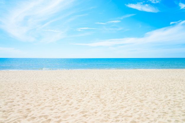 a sandy beach with blue sky and ocean in the background