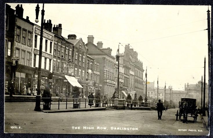 an old black and white photo of people walking down the street in front of buildings