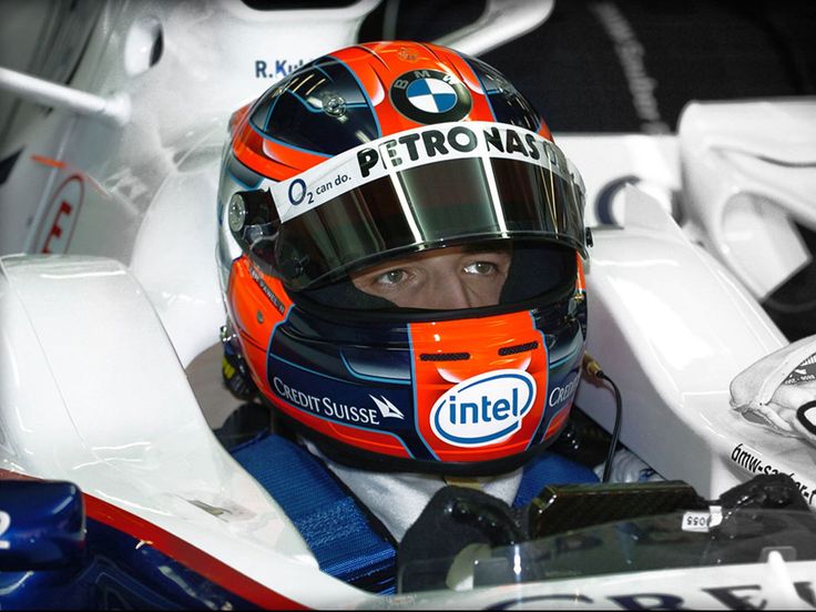 a close up of a person wearing a helmet and sitting in a car with other cars behind him