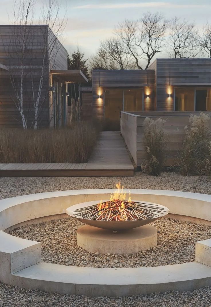 an outdoor fire pit in the middle of a gravel area with steps leading up to it