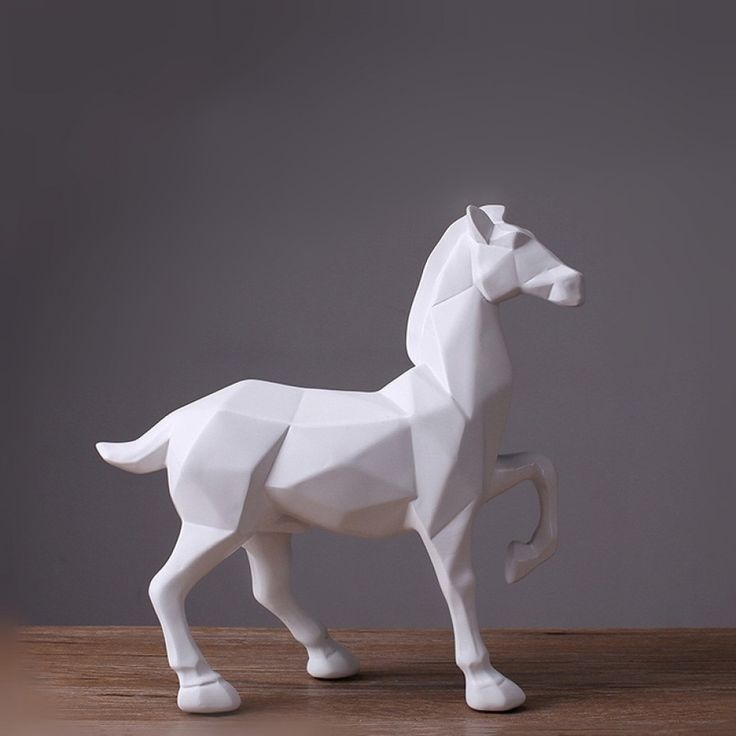 a white horse statue sitting on top of a wooden table next to a gray wall