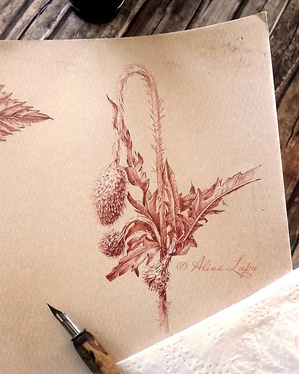 a pen and some paper on top of a wooden table with an inking technique