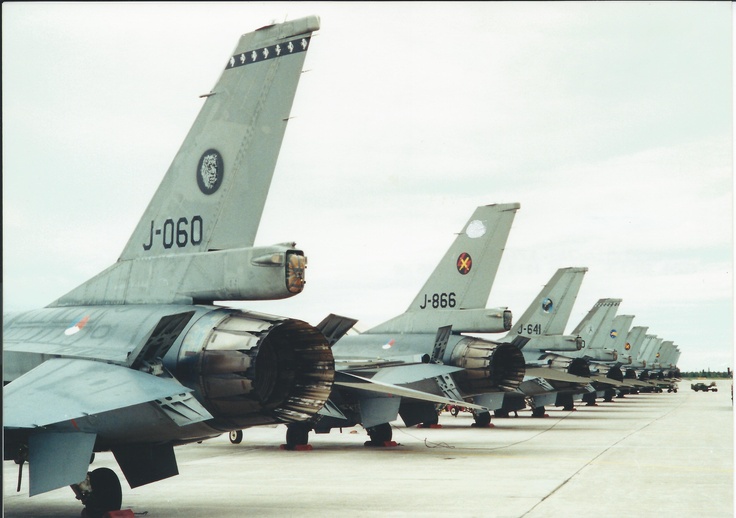 a row of fighter jets sitting on top of an airport tarmac next to each other