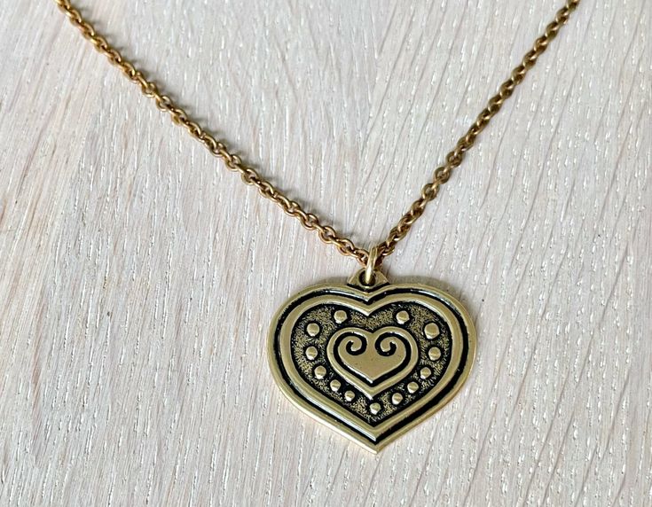 Kalevala jewelry bronze heart necklace. This gorgeous "Euran Sydän" (Eura Heart) bronze necklace would make a perfect gift for someone you love. Pendant width 3.2 cm (1.3"), length 3 cm (1.18") Chain length: 70 cm (approx. 27.6") Very good vintage condition. Comes in a small cardboard box like in the last photo making this a great gift! Kalevala Koru was established in 1937 and it is the most beloved jewelry company in Finland. Kalevala jewelry has always been hand-made in Finland by skilled art Bohemian Heart Pendant Charm Necklace Gift, Antique Gold Necklace With Heart Charm For Valentine's Day, Engraved Antique Gold Necklaces For Valentine's Day, Bronze Heart Necklaces For Valentine's Day, Bronze Heart-shaped Necklace For Valentine's Day, Antique Gold Heart Pendant Necklace For Valentine's Day, Antique Gold Heart Necklace For Valentine's Day, Valentine's Day Brass Heart Pendant Necklace, Valentine's Day Heart Pendant Necklace In Brass